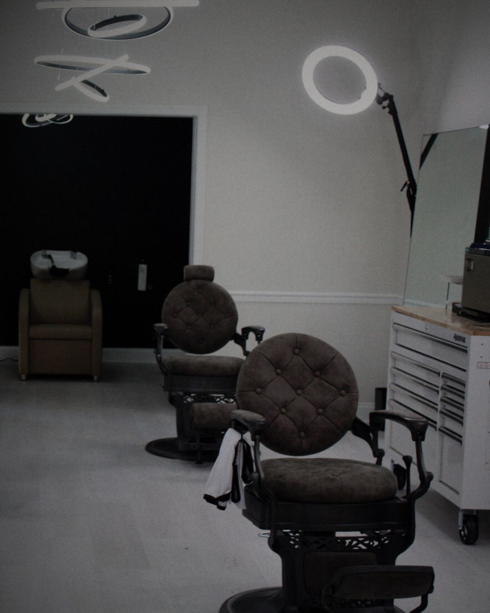 A round, button-tufted barber chair with an ornate black base