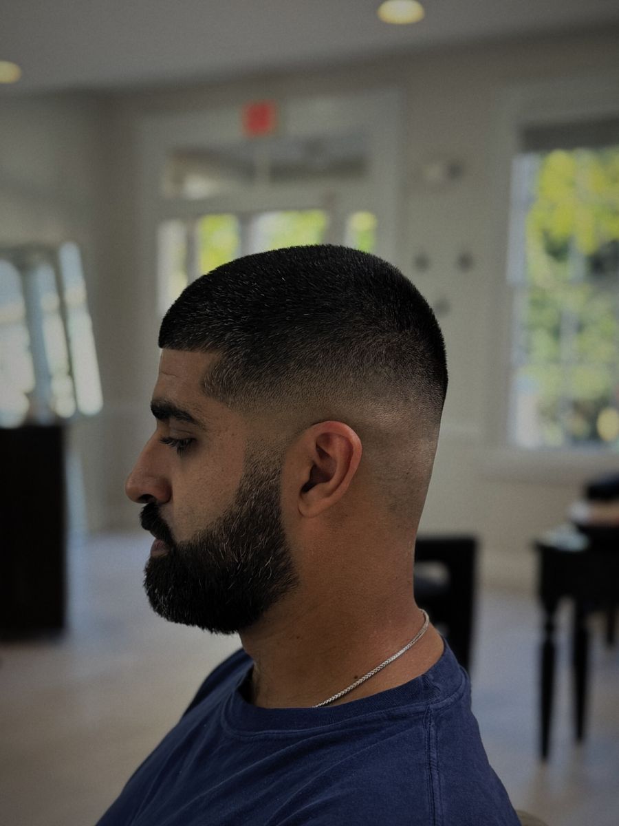 Skin fade with a full, shaped beard, in profile