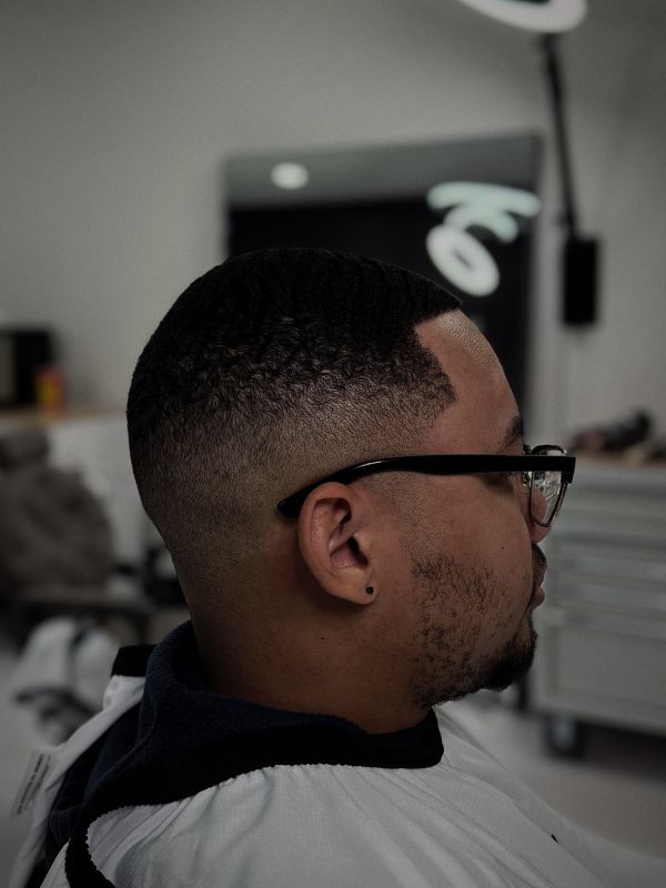 High skin fade with a sharp line-up, client wearing glasses