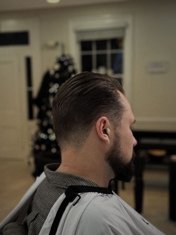 Slicked-back cut with tapered sides and a beard