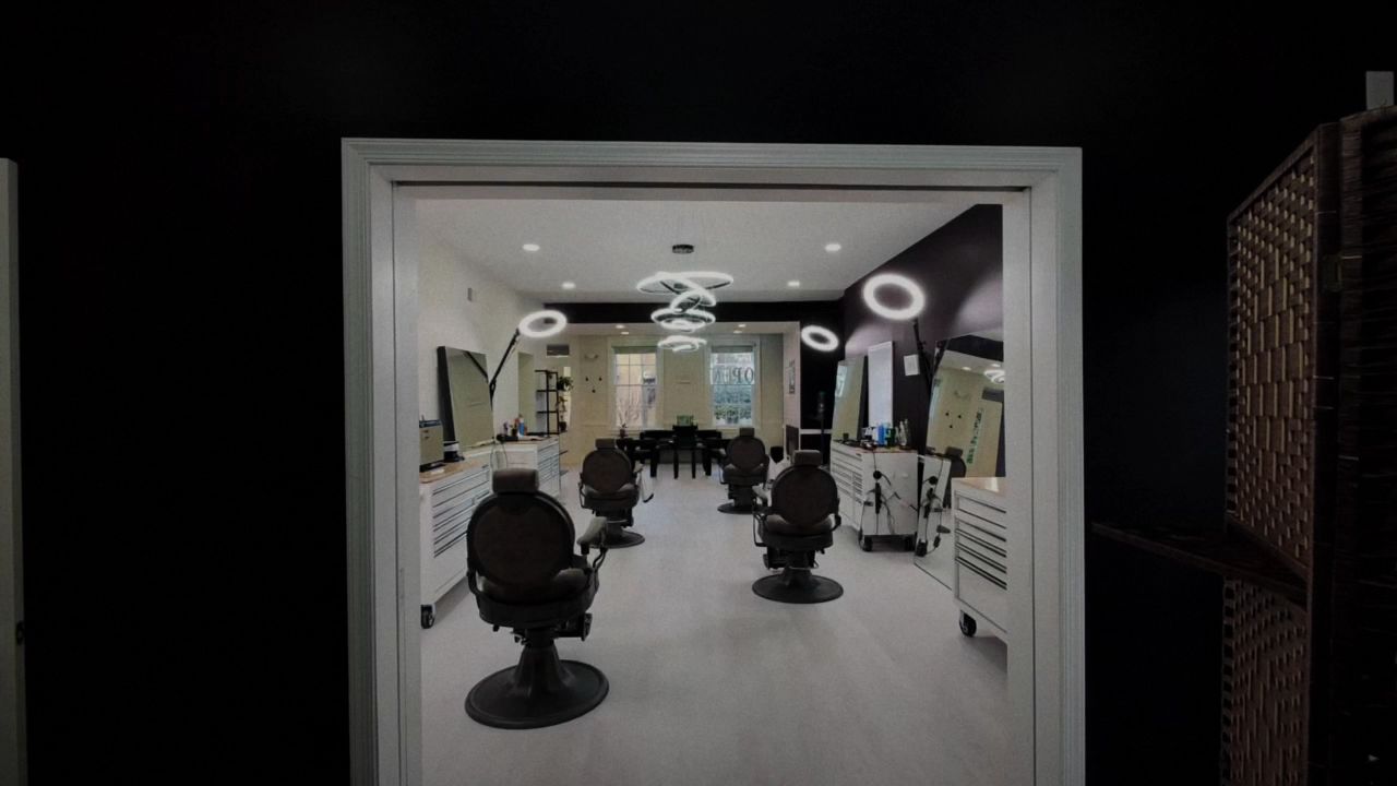 Looking through a doorway from VQ's dark back room into the lit studio of round barber chairs