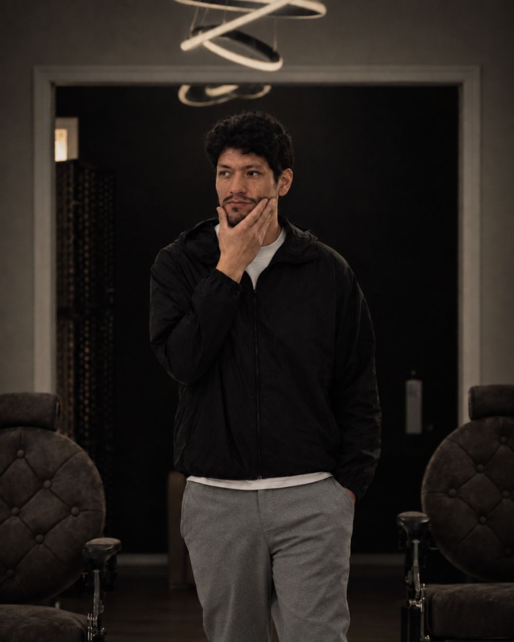 Josue Alegria, owner and master barber, standing in the doorway at VQ between two barber chairs