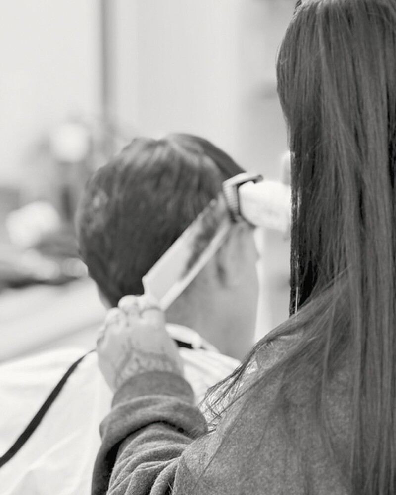 A barber at work at VQ, clippers in hand