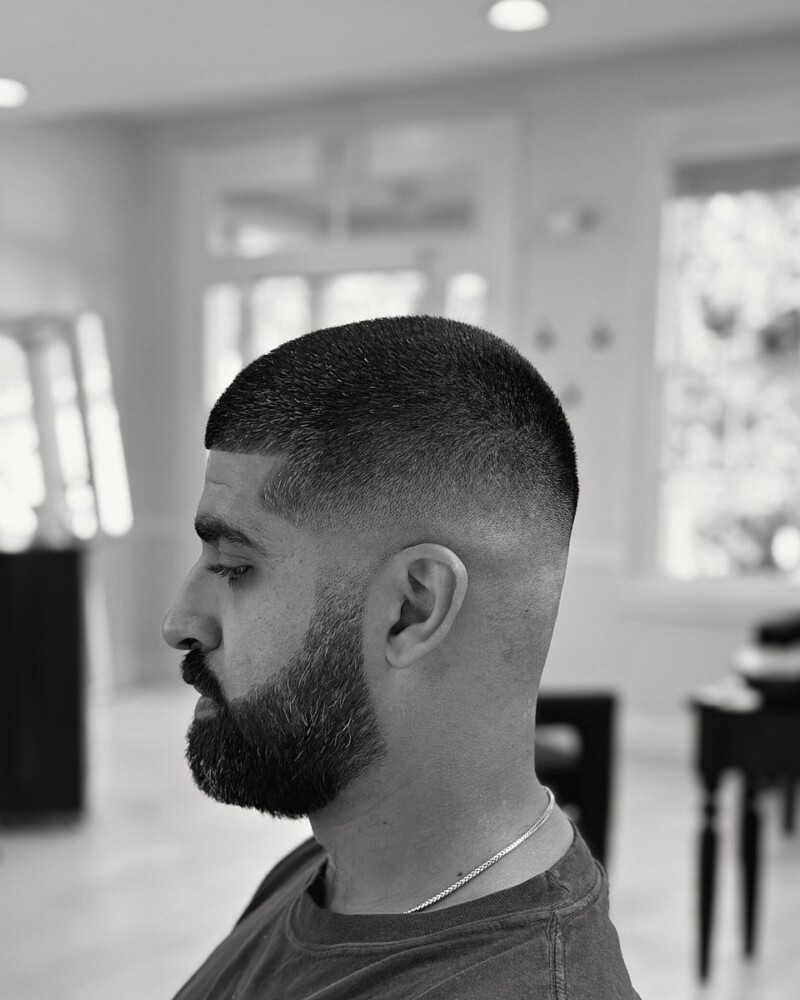 Skin fade with a full, shaped beard, in profile