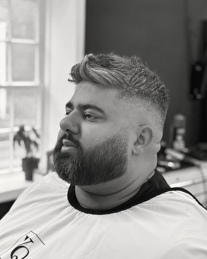 Mid fade with a textured top and a full beard