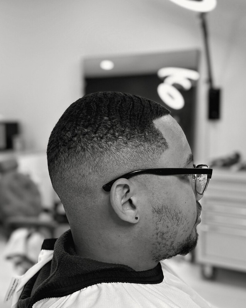 High skin fade with a sharp line-up, client wearing glasses
