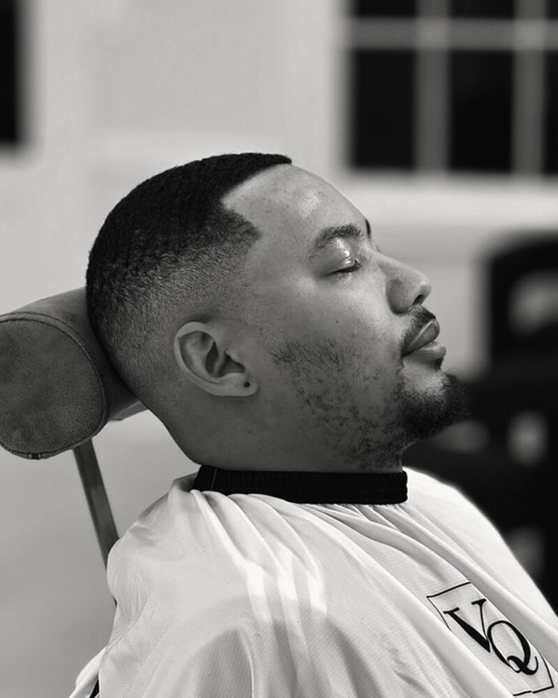 Skin fade with a crisp line-up, head resting back