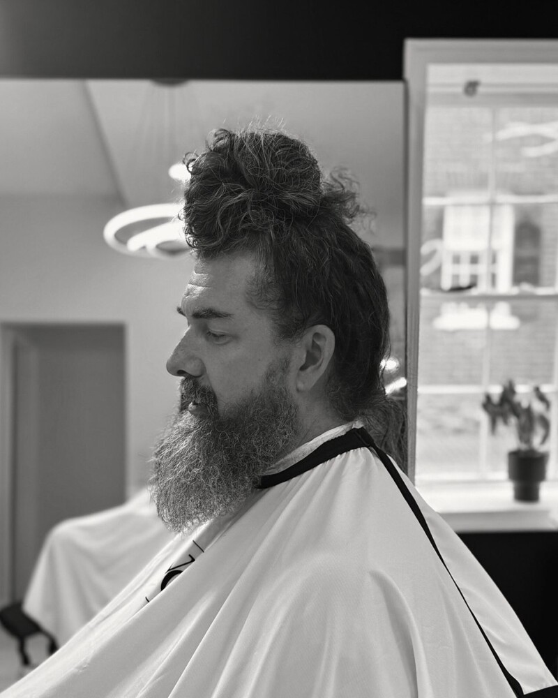 Long hair tied in a top knot with a long beard