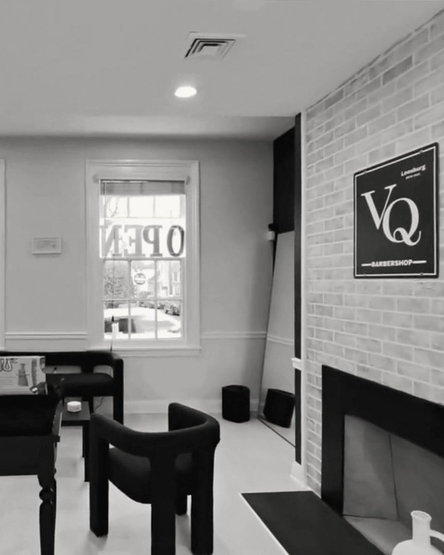 VQ's front room: black armchairs, the VQ sign on a white brick fireplace wall and the front windows
