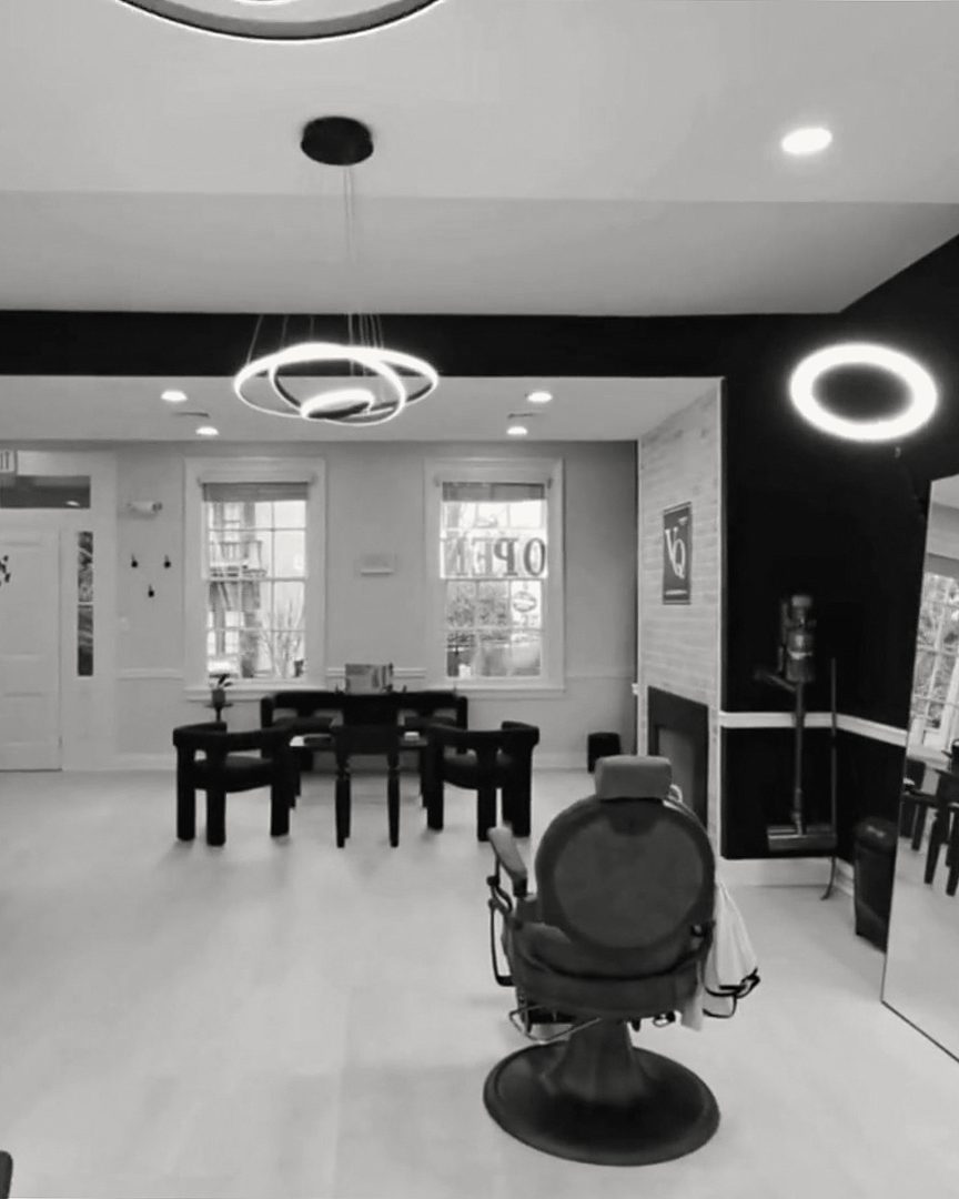 A barber chair beside a mirror, looking toward the front room and windows