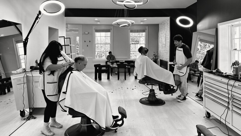 A busy afternoon at VQ: two barbers at work under the ring lights